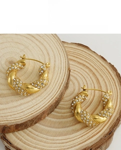 Detailed close-up of 18k gold-plated twisted hoop earrings with micro-pave crystals