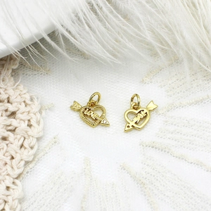 Macro shot of gold Cupid arrow heart charms with LOVE engraving for jewelry making
