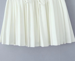 Detailed view of white pleated skirt texture with delicate waist drawstring accents