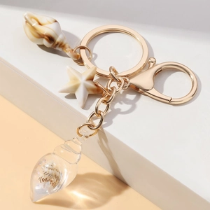 Detailed view of glow-in-the-dark conch and starfish keychain with golden hardware