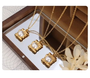 Close-up of golden pearl pendant necklaces displayed on a vintage mirror tray