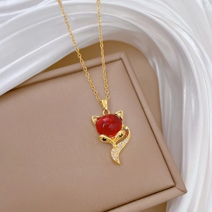 Detailed shot of golden fox necklace with red gemstone and diamonds on silk background