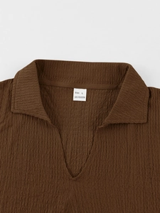 Detail of V-neck collar on brown seersucker short sleeve shirt showing crinkle texture