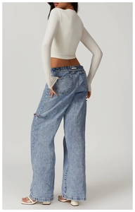Detail shot of light blue high-waisted distressed wide-leg jeans with ripped thigh design