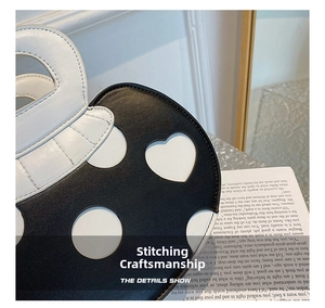 Close-up of heart-shaped cutouts and white contrast stitching on a black leather bag