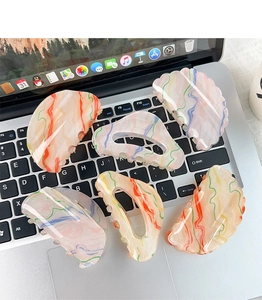 Detailed view of six artistic acrylic hair claws with oil painting patterns on a laptop