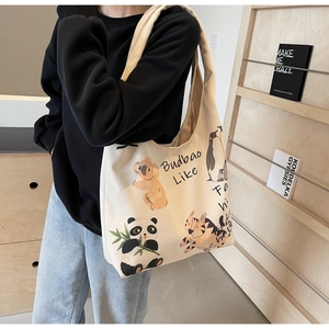 Detail shot of cream canvas tote bag featuring cute cartoon animal illustrations