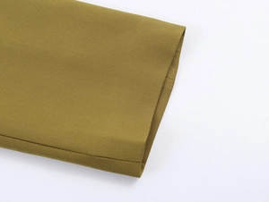 Close-up detail of the army green fabric texture and sleeve cuff of the elegant blazer