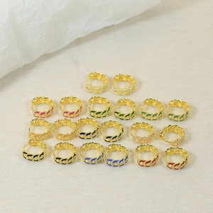 Macro shot of colorful enamel link earrings with zircon inlay on beige fabric background