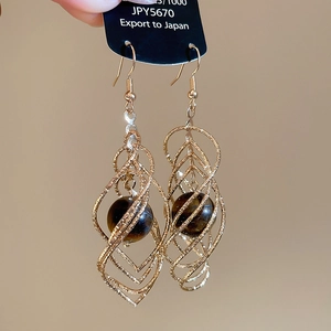 Detailed shot of twisted golden diamond frame with tiger eye stone drop earring