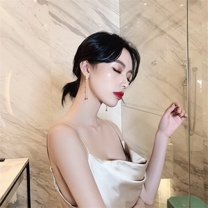 Close-up of elegant long pearl tassel drop earrings on a model with silk dress
