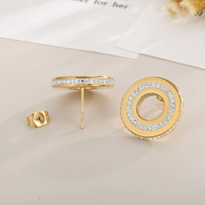 Macro detail of gold-plated circular stud earrings featuring micro-set sparkling crystals