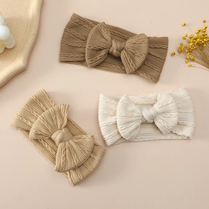 Three-pack knit baby headbands with large bows and vintage cable knit texture in warm tones