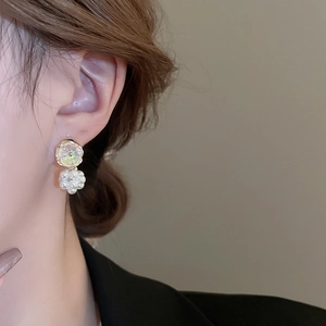 Close-up of floral iridescent gem and white cluster pearl drop earrings for women