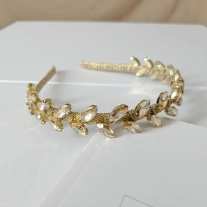 Close-up of golden headband with champagne marquise rhinestones in leaf patterns