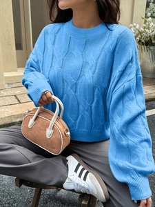 Detail of blue cable knit sweater with ribbed round neck and textured pattern