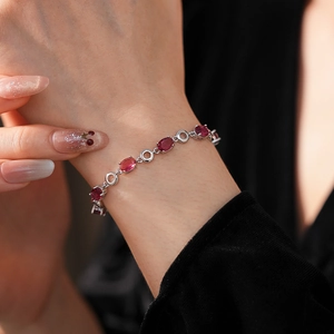 Detailed view of silver bracelet with oval red gemstones and hollow ring connectors