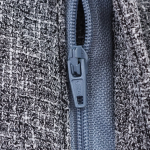 Close-up of grey zipper on tweed two-piece suit set with textured woven fabric