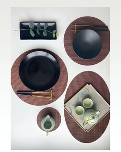 Flat lay of woven bamboo table mats with elegant ceramic teaware and dining set