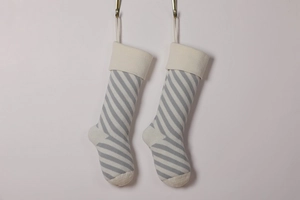 Close-up of grey and white striped knitted Christmas stockings with beige cuffs and toes