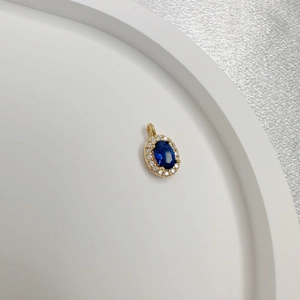 Detailed view of an oval blue gemstone pendant with gold plating and sparkling small crystals