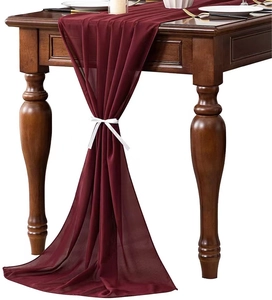 Detail view of burgundy chiffon table runner draped elegantly with white silk ribbon tie