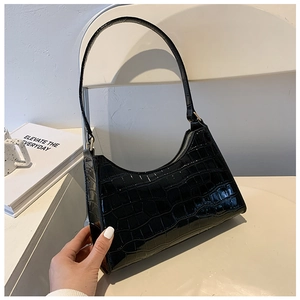Close-up of black crocodile pattern faux leather baguette bag on a white chair
