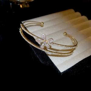 Detailed close-up of double-layered gold bangle with zircon flower on jewelry box
