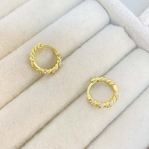 Classic gold twisted hoop earrings with micro-set zircon stones on jewelry display stand