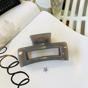 Macro shot of minimalist translucent grey rectangular claw clip on a white magazine