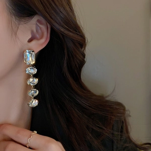 Elegant gold drop earrings with five cascading square and oval crystals on a model