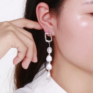 Gros plan d'une femme portant des boucles d'oreilles géométriques en argent et perles