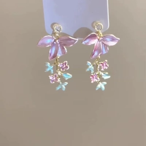 Detailed close-up of blue and pink enamel flower earrings with gold plating and rhinestones