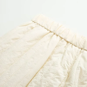 Detail of off-white quilted trousers featuring an elastic waistband and premium stitching
