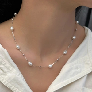 Close-up of minimalist silver pearl necklace featuring irregular freshwater pearls on a model