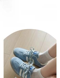 Close-up of white mesh ballet socks paired with blue suede vintage sneakers on wood
