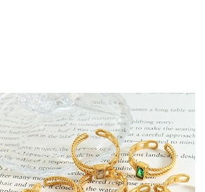 Detailed macro view of gold-plated rings featuring emerald green and white zircons