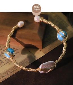 Detailed shot of handmade gold wire-wrapped bracelet with natural pearls and blue turquoise