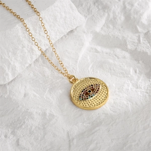 Macro shot of gold plated evil eye pendant with colorful cubic zirconia on stone