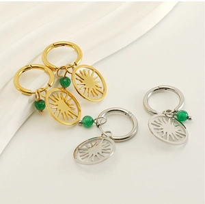 Detail of sunburst drop earrings with green stone beads in gold and silver finishes