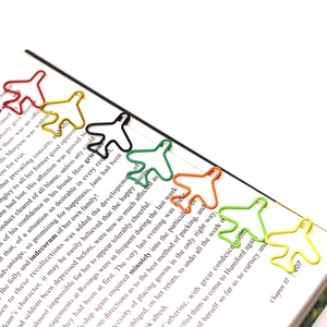 Detailed view of colorful airplane-shaped paperclips used as bookmarks on an open book
