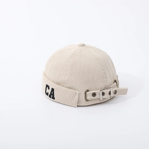 Detailed close-up of beige corduroy baby beanie with CA embroidery and adjustable buckle