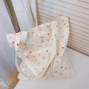 Detail of cream canvas tote bag featuring red floral patterns and a minimalist fabric label