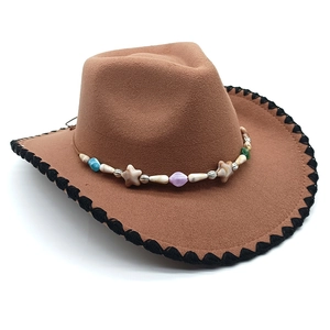 Detail of a brown felt cowboy hat featuring ethnic colorful beaded band and black stitched edge