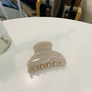 Close-up of a beige glossy heart-shaped hair claw clip with smooth curved teeth