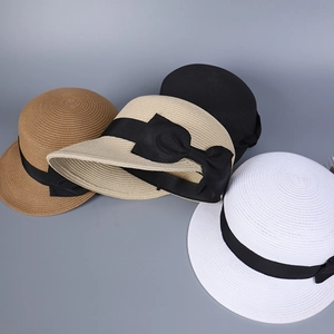 Dettaglio delle texture di quattro cappelli da sole in paglia intrecciata con fiocchi neri