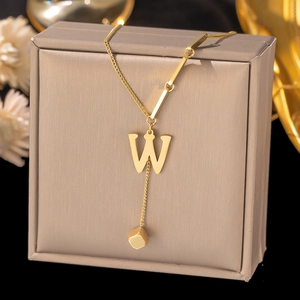 Detail view of 18K gold plated letter W pendant with minimalist cube tassels and chain