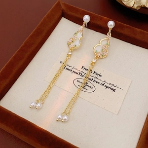 Elegant gold gourd tassel earrings with pearls and pink flower details on velvet