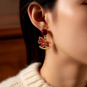 Detail of red bead and golden rocking horse earrings with festive Chinese lucky characters