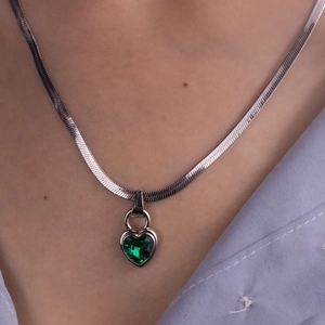 Close-up of heart-shaped emerald pendant necklace with a silver snake chain on a neck